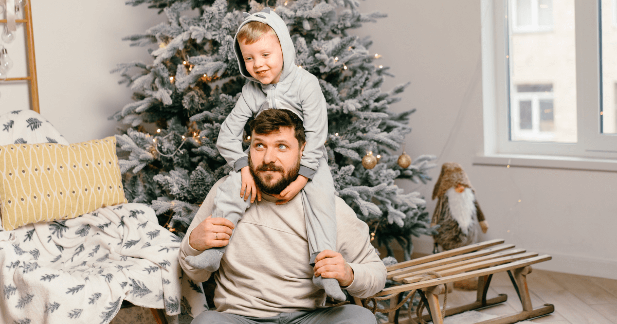 Father and child sitting by a decorated Christmas tree during the holiday season | Sip2Sleep®