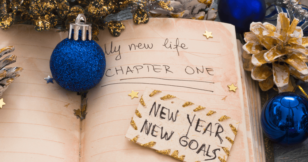 Open book with New Year's goals and resolutions written, surrounded by festive blue and gold decorations