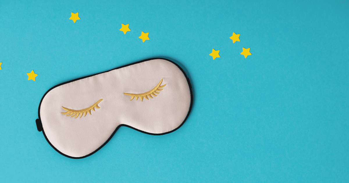 Pink sleeping mask and paper stars on blue background