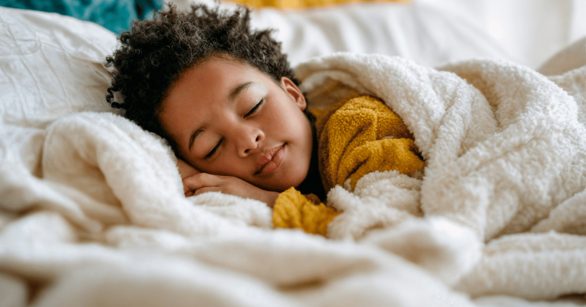 Child sleeping peacefully in bed with white blanket