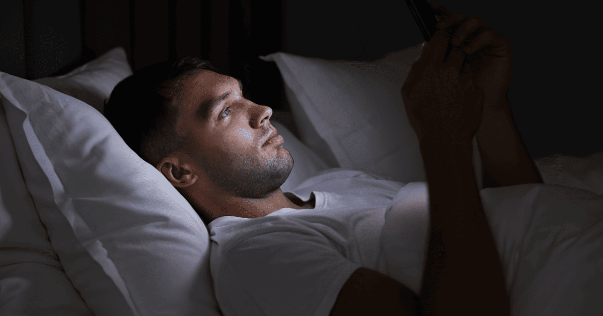 Man using smartphone in bed at night