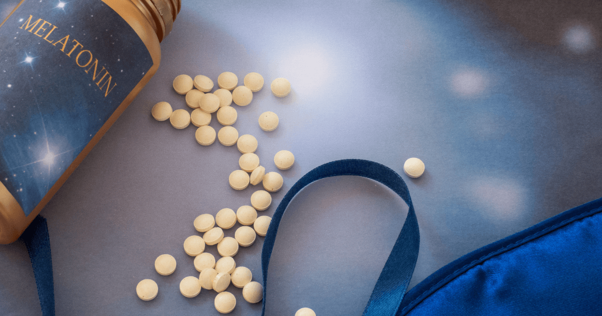 Melatonin pills scattered on a surface next to a pill bottle and a sleep mask | Sip2Sleep®