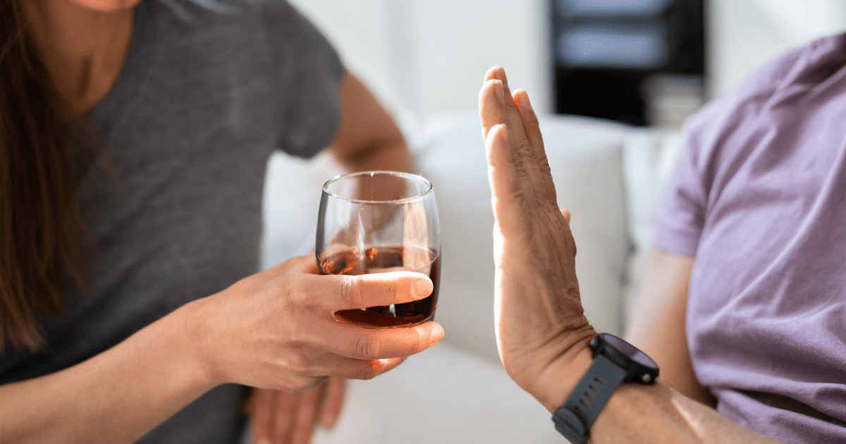 Person refusing a glass of alcohol before bedtime, highlighting the connection between drinking and sleep