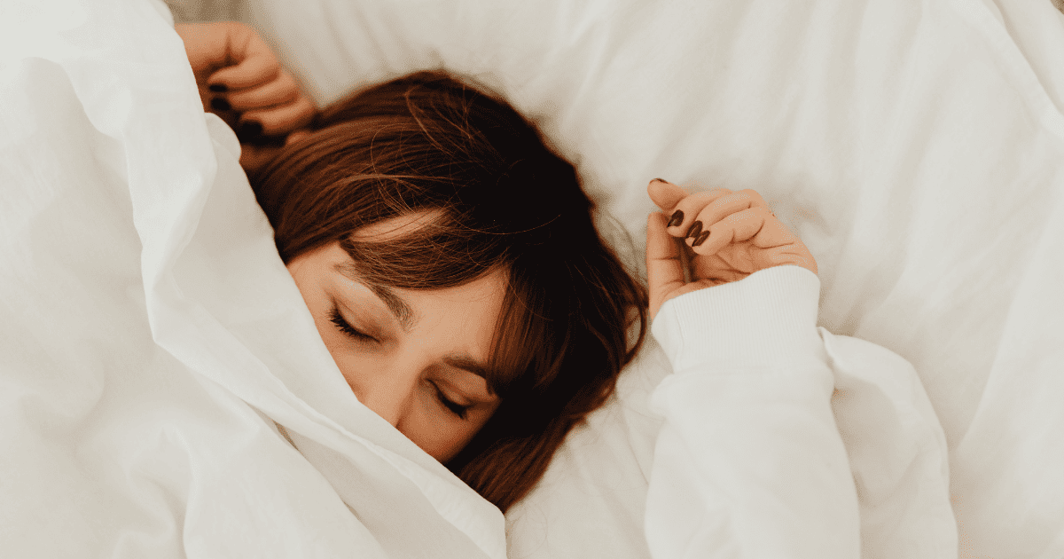 Women lying on bed covering her face with blanket and sleeping peacefully