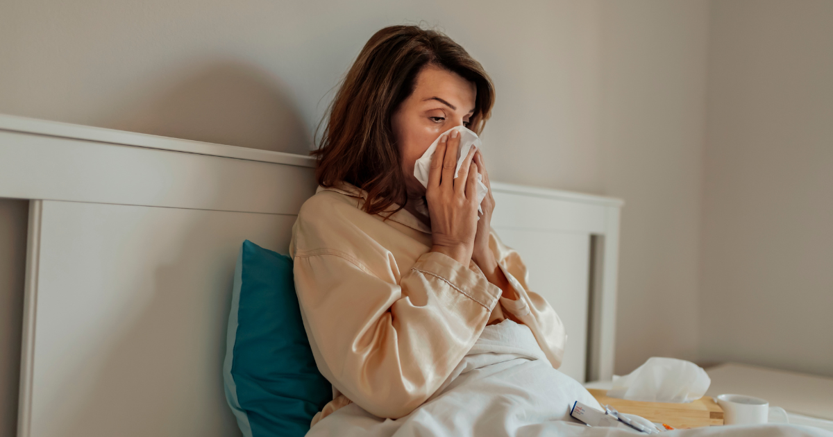 Woman with cold blowing nose in bed after poor sleep compromised her immune system | Sip2Sleep®