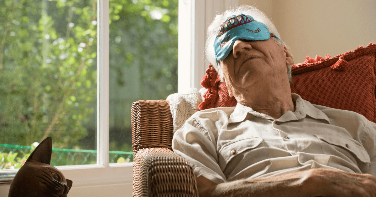 Older man wearing a sleep mask while napping in a chair | Sip2Sleep®