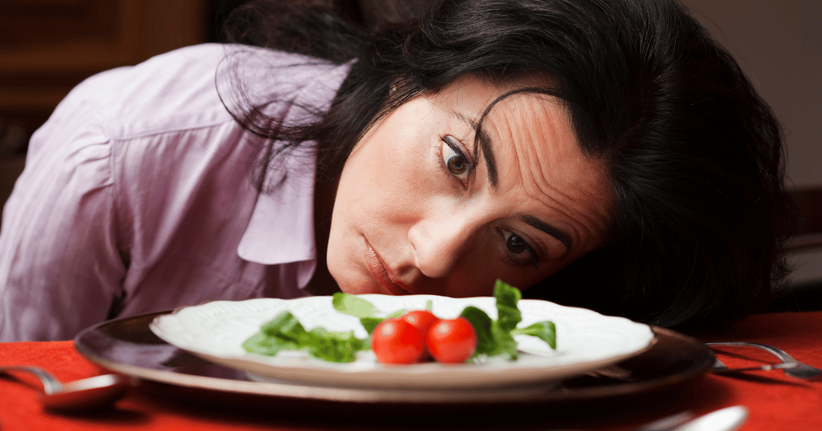 Tired woman leaning beside a low-carb keto meal, illustrating keto insomnia and sleep problems.