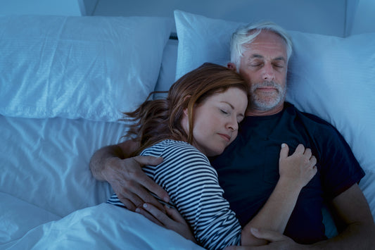 A middle-aged couple peacefully sleeping in bed, illustrating the importance of deep sleep for brain health and cognitive function.