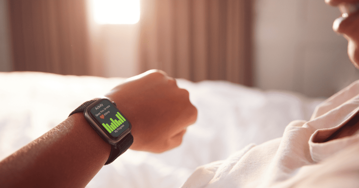 Man checking his smartwatch in bed after waking up